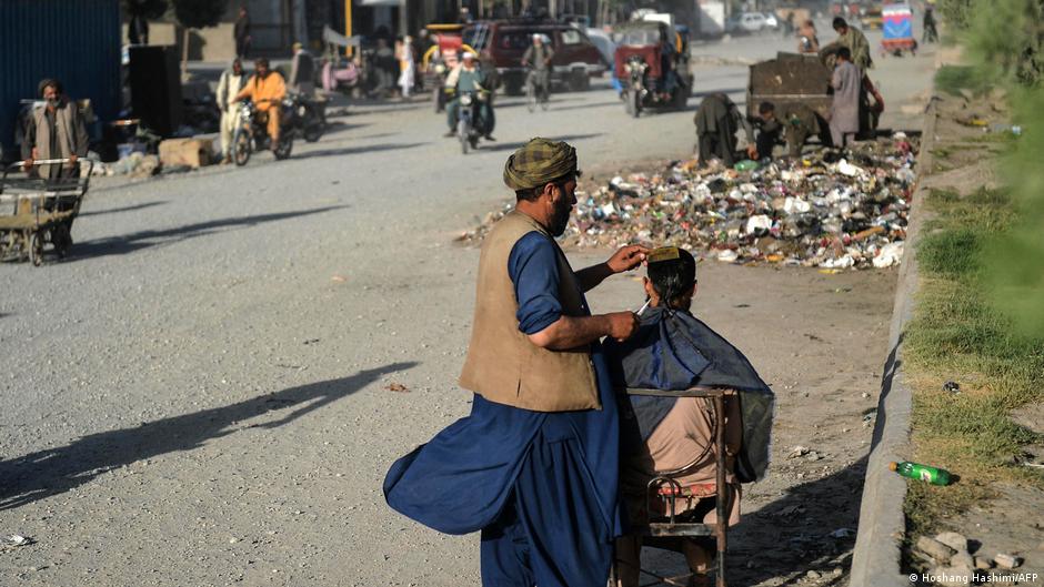  this photo taken on June 9, 2021, a barber cuts the hair of a customer along a road in Herat (photo: Hoshang Hashimi/AFP)
