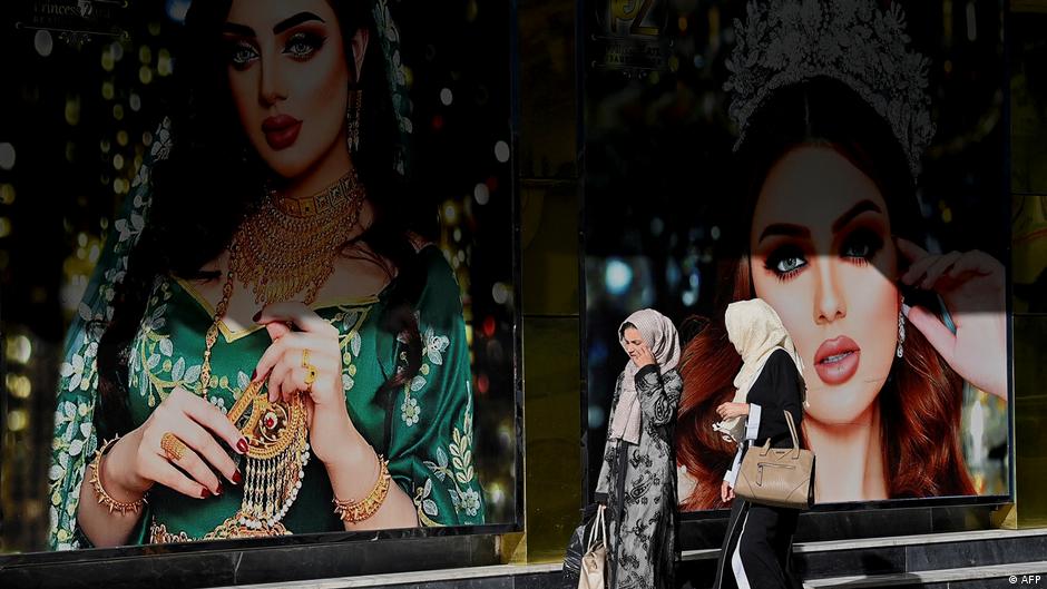 In this photo taken on June 10, 2021, women walk past a beauty parlour in Kabul (photo: Adek Berry/AFP)