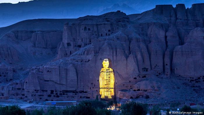 Projection of a shining golden Buddha figure in front of a mountain