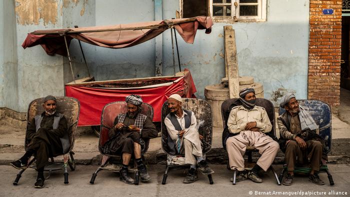 Male day labourers sit at the roadside in Kabul awaiting a job offer
