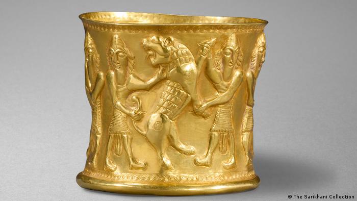 Ein goldenes Gefäß zeigt Männer, die Löwen festhalten.