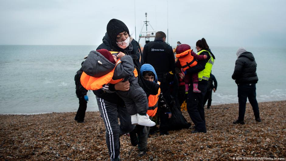 A woman helps her children after being brought ashore by an RNLI lifeboat after arriving at a beach in Dungeness on the south-east coast of England (photo: Ben Standsall/AFP/Getty Images)