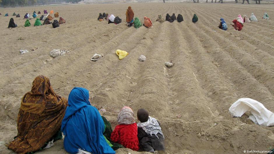 Afghan women and children sit in a field (photo: Safi/Xinhua/imago)