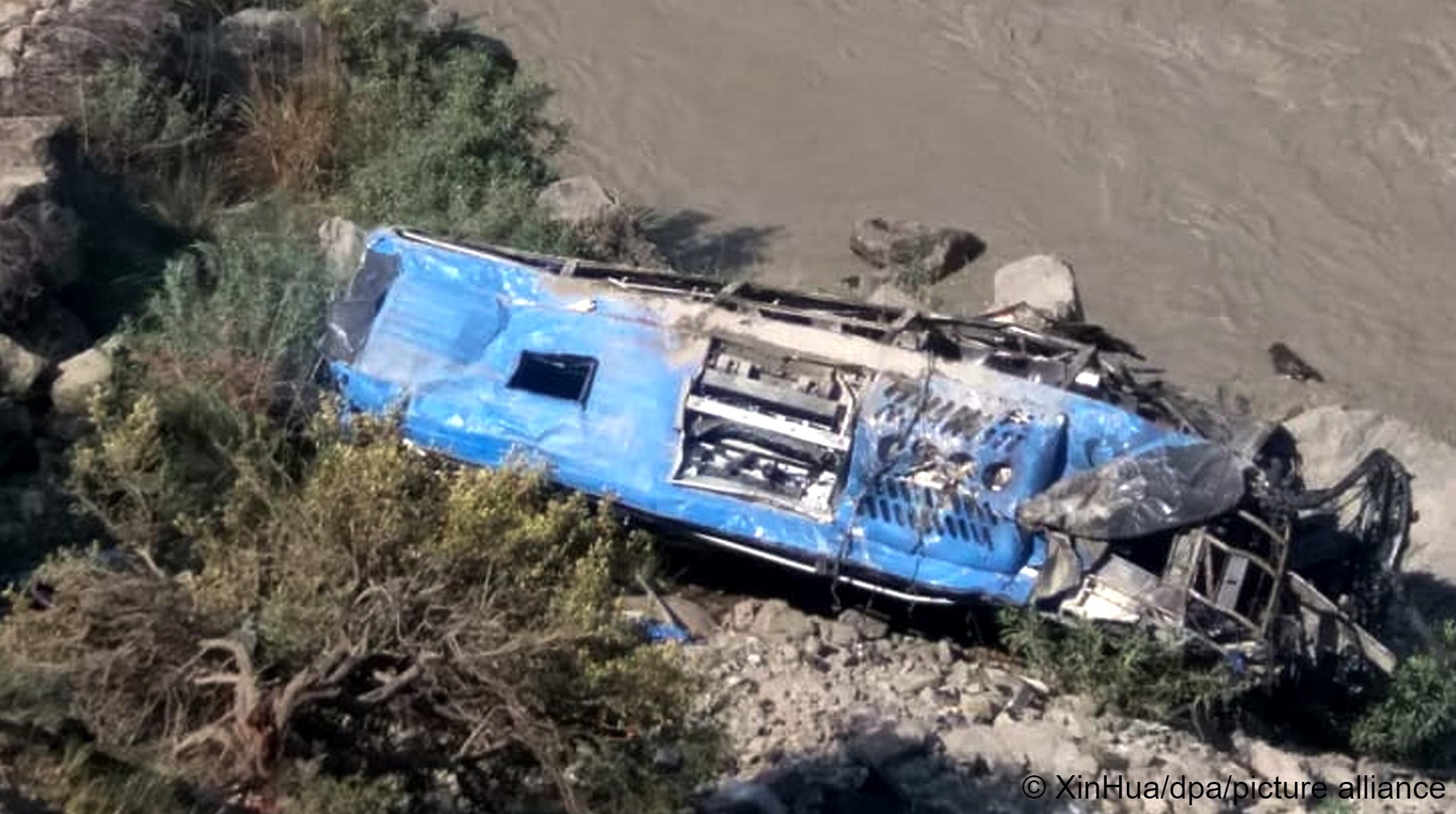The wreckage of a bus lies on rubble not far from a river. Thirteen people were killed in an explosion on a bus in northern Pakistan on 14 July 2021 (photo: dpa Bildfunk) 