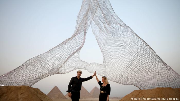 Italienische Künstler posieren unter ihrer Installation mit Blick auf die Pyramiden auf dem Plateau von Gizeh am 23. Oktober 2021