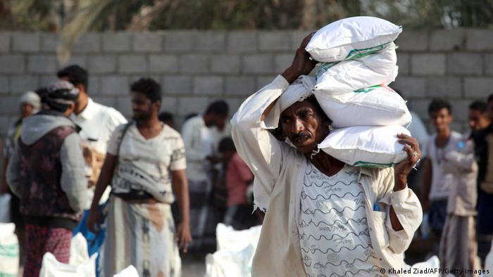 Yemeni workers carry bags of aid