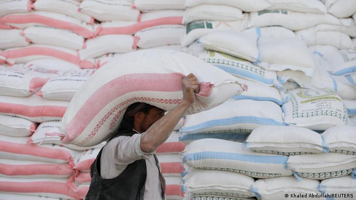 A worker carries a sack of wheat flour outside a wholesale food shop in Sanaa, Yemen