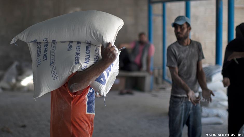 موظفو الأونروا يوزعون المواد الغذائية.  UNRWA-Mitarbeiter bei der Verteilung von Lebensmitteln; Foto: AFP/S. Khatib