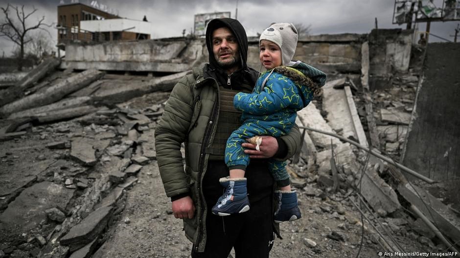 رجل يحمل طفلًا أثناء فراره من بلدة إيربين الواقعة غربي كييف - أوكرانيا.