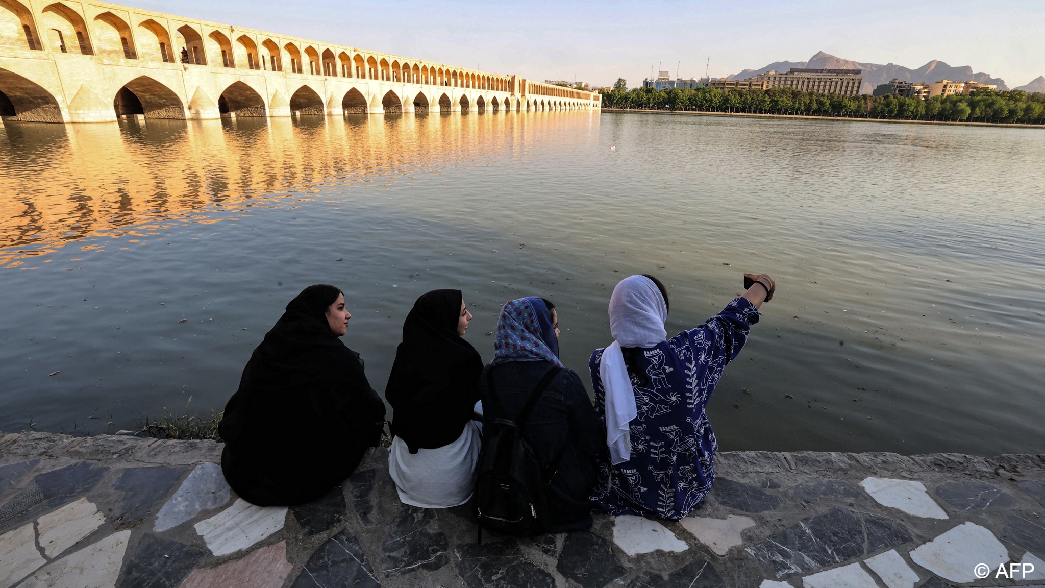 التقاط نساء صورة سلفي ذاتية على ضفة نهر زاينده في مدينة أصفهان وسط إيران - 15 مايو 2022. Women pose for a selfie along the bank of the Zayandeh Rood in Iran's central city of Isfahan on 15 May 2022 (photo: ATTA KENARE/AFP)