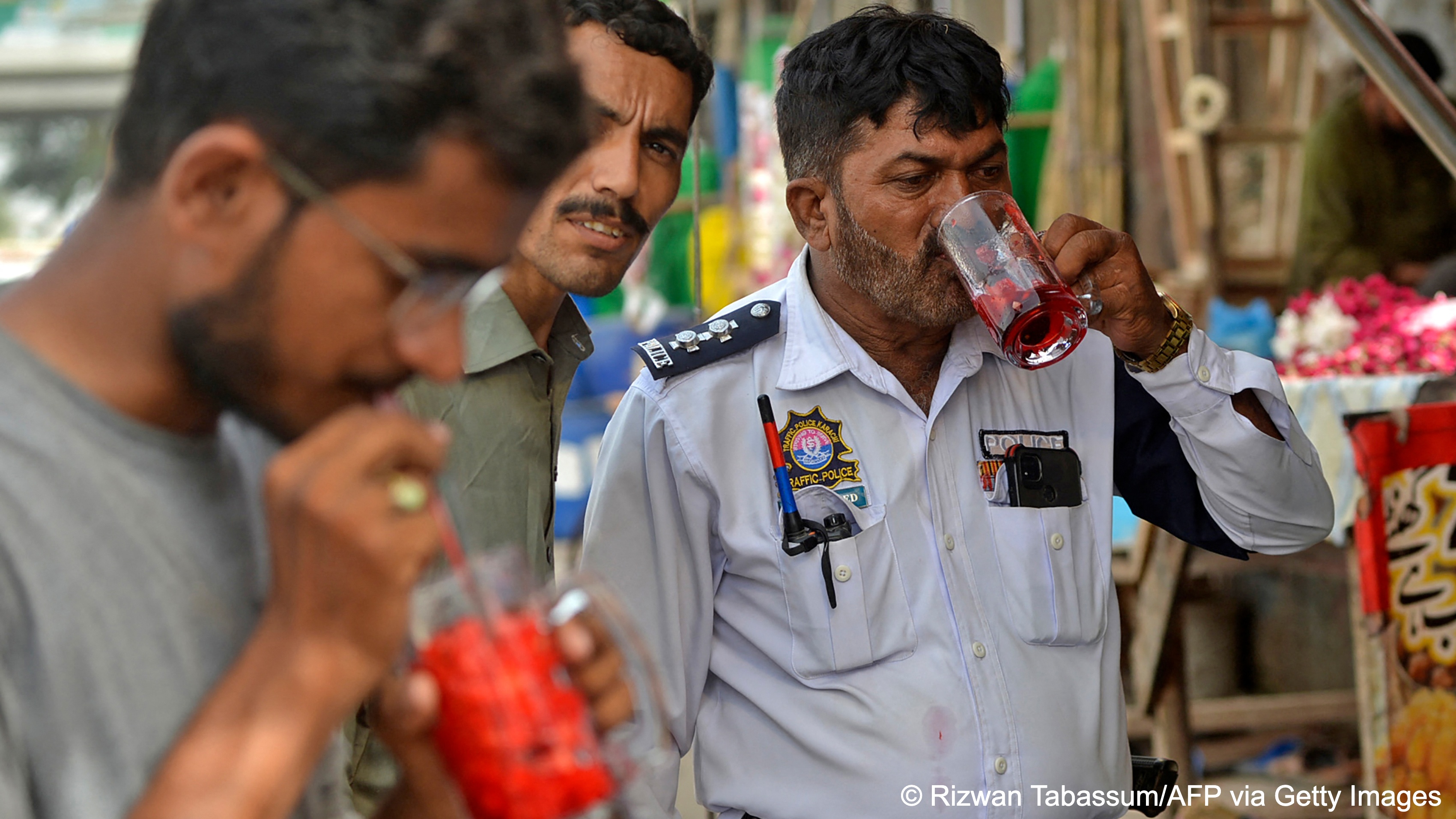Three men, one of them a policeman, quench their thirst with glasses of Rooh Afza in Karachi (photo: