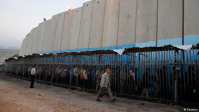 Palestinians from the Occupied Territories wait at the border wall to cross into Israel to work (photo: Reuters)