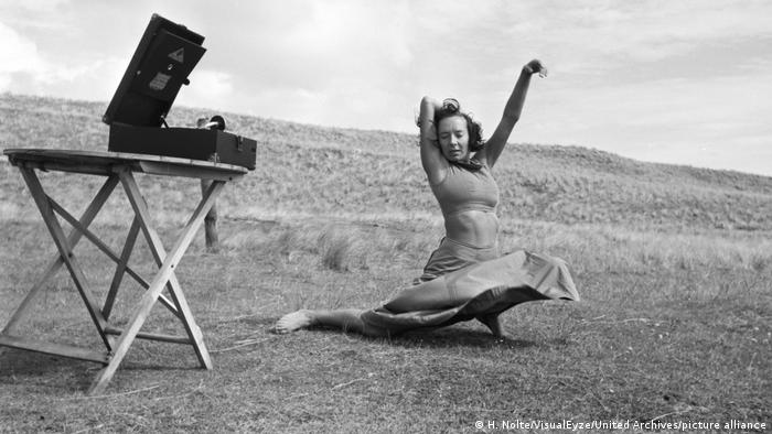 Die Tänzerin Gret Palucca tanzt in den 1930er-Jahren auf einem Feld, neben ihr steht ein Grammophon auf einem kleinen Tisch