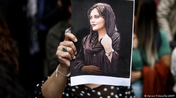 A woman holds up an image of Jina Mahsa Amini (photo: Kenzo Tribouillard/AFP)