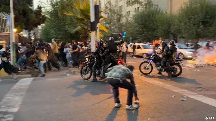 Baton-wielding police officers on motorcycles chase fleeing protesters (photo: AFP)