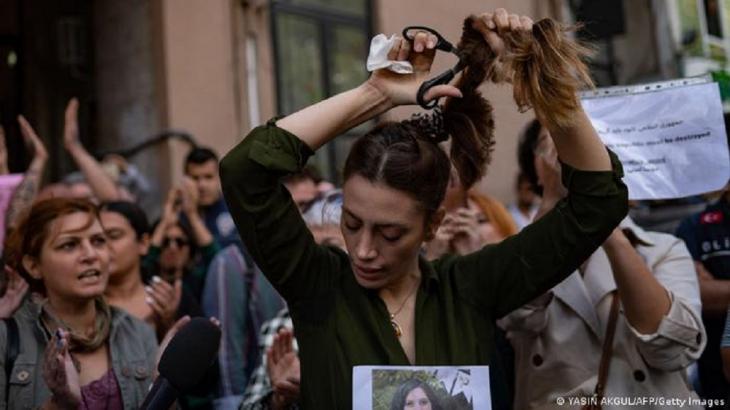 A woman cuts her hair during a protest (photo: YASIN AKGUL/AFP/Getty Images)