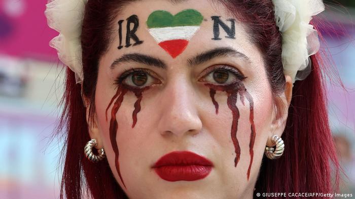A woman at the World Cup in Qatar with the word Iran and dark red tears painted on her face (photo: Giuseppe Cacace/AFP/Getty Images)