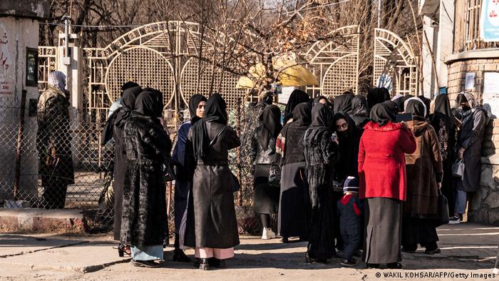 Vor den geschlossenen Gittertoren einer Universität in Kabul stehen zahlreiche Frauen, die meisten sind schwarz gekleidet.