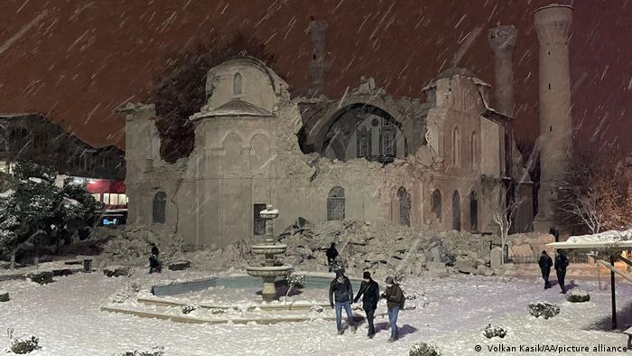 The roof and part of the outer wall of the mosque have collapsed, snow covers the ground and the building, it is snowing