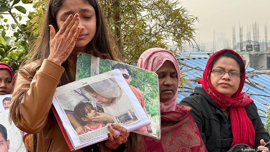 Ein junges Mädchen hält zwei Familienbilder in ihrer mit Henna bemalten Hand und weint; Foto: Arafatul Islam/DW