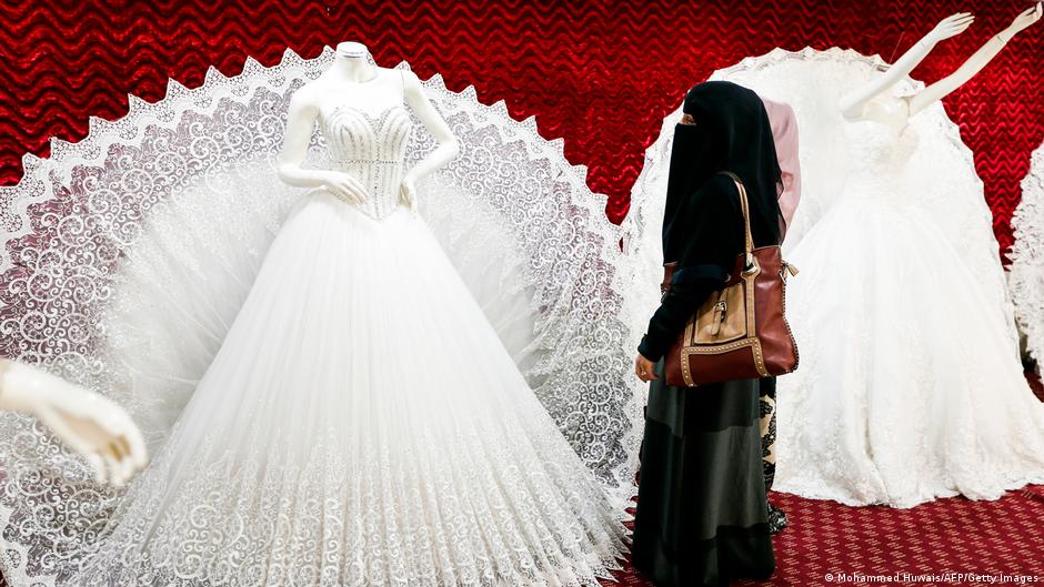 A veiled women looking at a bridal gown (image: Mohammed Huwais/AFP/Getty Images)