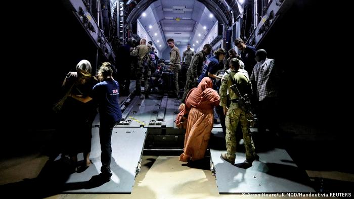 View of the cargo hold of an aircraft with people boarding in the dark and others already on board.