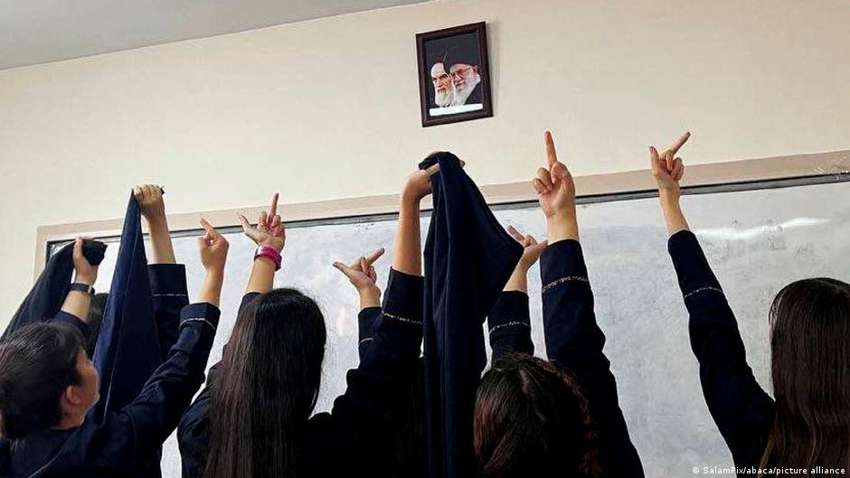 طالبات معارضات لنظام الخميني وخامنئي - إيران. Schülerinnen zeigen den "Stinkefinger" vor Porträts von Chomeini und Chamenei/Foto: SalamPix/Abaca/picture-alliance
