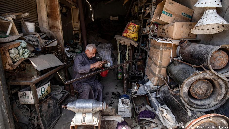 Man sits working in a very basic metal-working shop (image: DELIL SOULEIMAN AFP via Getty Images) 