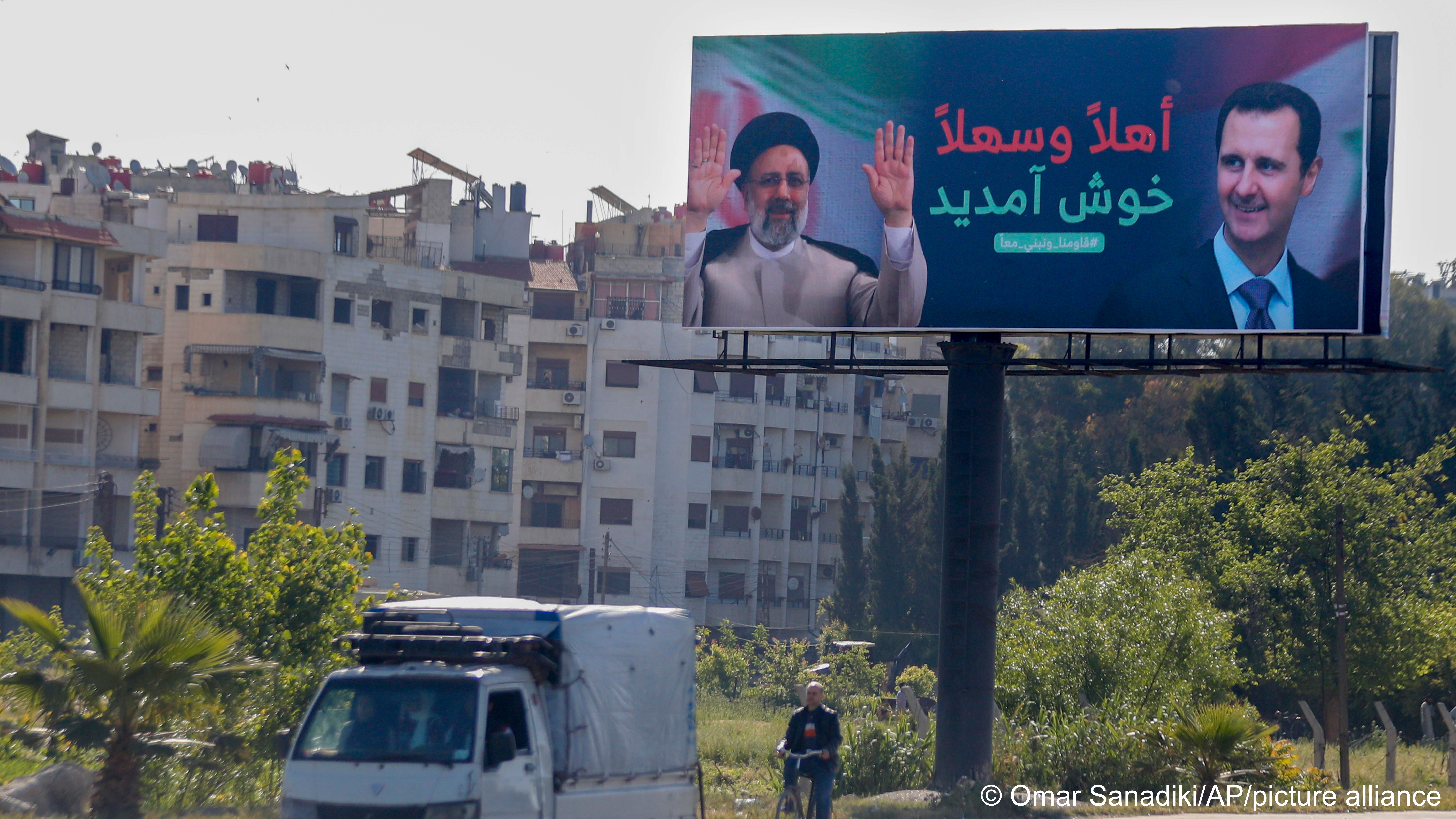  People drive beneath a poster with pictures of Iranian President Ebrahim Raisi (left) and Syrian President Bashar al-Assad that reads “Welcome” in Arabic, Damascus, Syria, 3 May 2023 (photo: Omar Sanadiki/AP/picture alliance)
