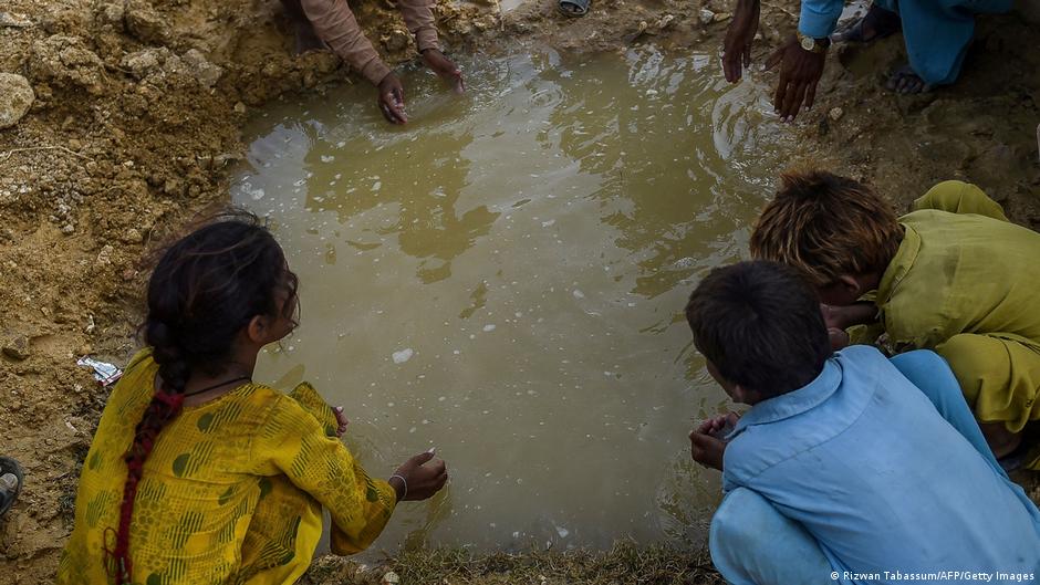 Children of internally displaced flood affected people drink water from a puddle outside a makeshift camp in Jamshoro district of Sindh province, Pakistan, September 2023 (image: Rizwan Tabassum/AFP/Getty Images)