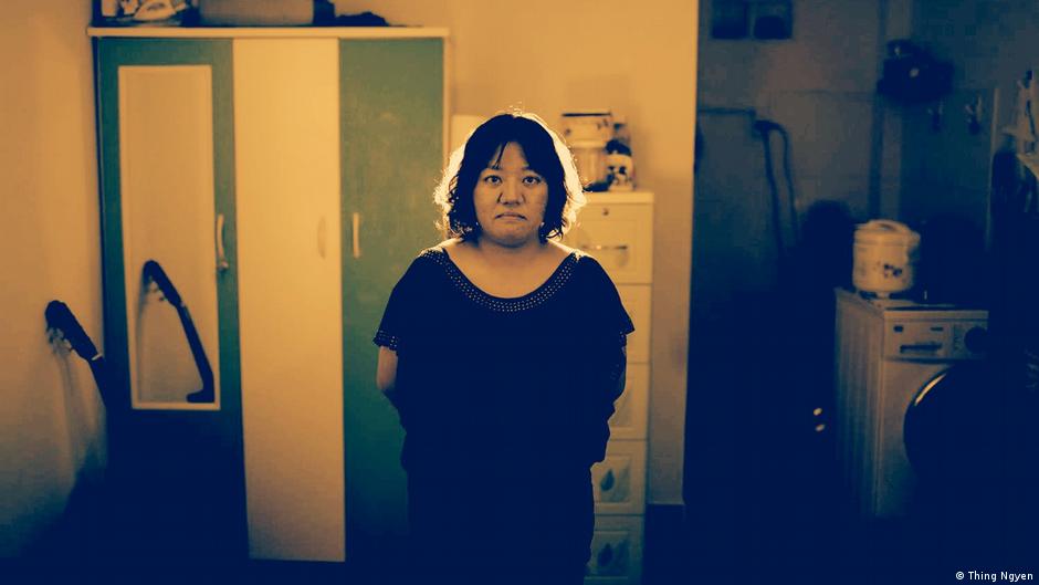 Pham Doan Trang, a frowning woman stand in a room, closets and a washing machine in the background