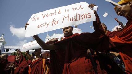 A Myanmar Buddhist monk holds a sign saying 'The world is not only for Muslims' as he takes part in a demonstration against the Organisation of the Islamic Conference in Yangon on October 15, 2012 (photo: AFP PHOTO/Ye Aung Thu)
