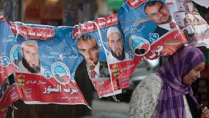 Ägypterin passiert aufgehängte Wahlplakate mit Kandidaten der islamistischen Al-Nour-Partei; Foto: AP/dapd