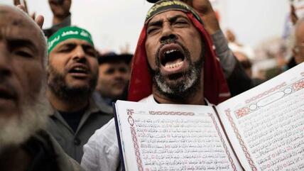 Anhänger Mohammed Mursis hält während einer Demonstration in Kairo den Koran hoch; Foto: AFP/Getty Images