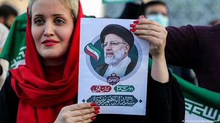 A woman holds a picture of Iran's newly-elected president Ebrahim Raisi as supporters celebrate his victory in Imam Hussein square in the capital Tehran on 19 June 2021.