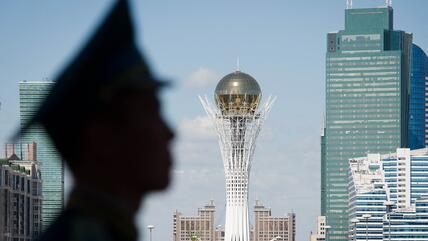 Der Byterek Turm ist sichtbar im Zentrum von Astana als ein Soldaten außerhalb des Präsidentenpalastes in Astana, Kasachstan, Wache steht, 1. Juli, 2013. David Cameron besuchte Kasachstan am 30. Juni 2013, es war der erste Besuch eines britischen Premierministers, um die Handelsbeziehungen zwischen beiden Ländern zu vertiefen, aber auch um Menschenrechtsfragen anzusprechen.  TOPSHOTS  AFP PHOTO/POOL/ LEON NEAL (Foto by LEON NEAL / POOL / AFP)