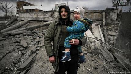 رجل يحمل طفلًا أثناء فراره من بلدة إيربين الواقعة غربي كييف - أوكرانيا.