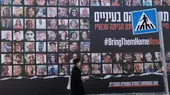 A woman walks past a billboard showing photos of hostages taken by Hamas on 7 October and featuring the hashtag #BringThemHomeNow