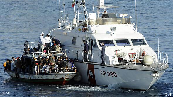 An overcrowded boat full of migrants alongside a boat belonging to the Itlian coast-guard (photo: AP)