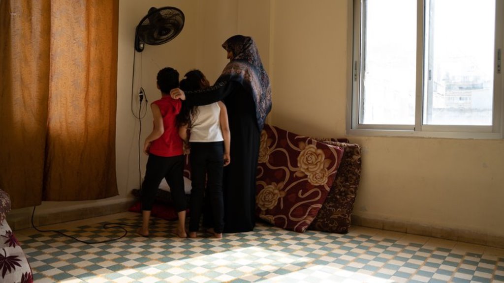 Salha Khalaf Mohamed mit zweien ihrer Kinder im Schlafzimmer: Durch die Explosion wurden die Bettgestelle zerstört, nun schlafen sie auf Matratzen auf dem Boden. Foto: Andrea Backhaus