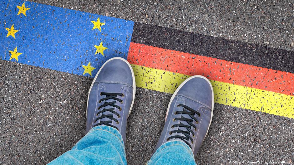 A man stands on tarmac painted with a German national flag and the European flag (image: Oliver Boehmer/Zoonar/picture alliance)