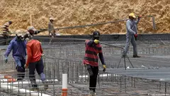 Workers carry metal bars on a construction site in Riyadh